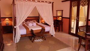 A four-poster canopy bed with a wooden headboard, a woven chair, and a small table with a lamp. - Swaloh Hill Resort (Mulyosari)