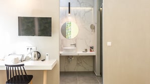 A modern bathroom with a marble sink, a round mirror, a handheld showerhead, and a toilet. - Ark 68 City Rooms (Rethymno)