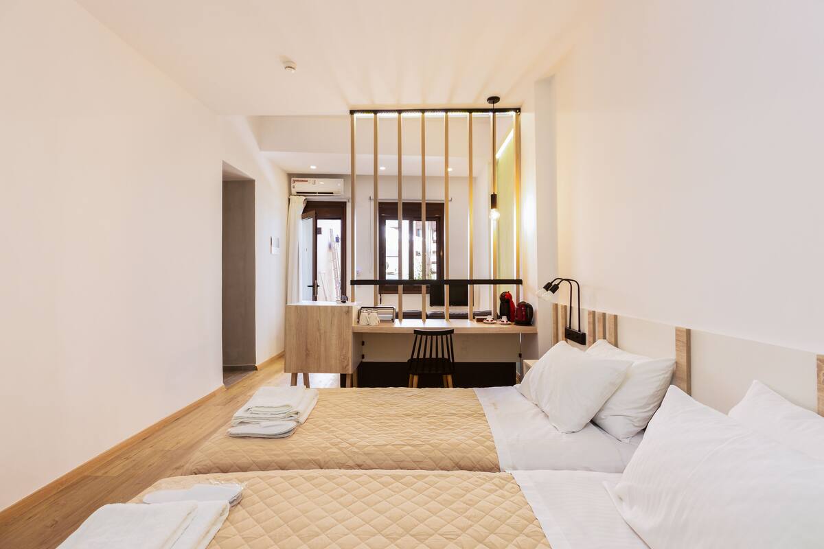 A hotel room with two beds, a desk, and a chair.