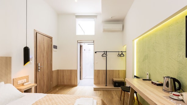 A modern hotel room with a bed, a desk, a chair, a small table, a kettle, and a cup. - Ark 68 City Rooms (Rethymno)