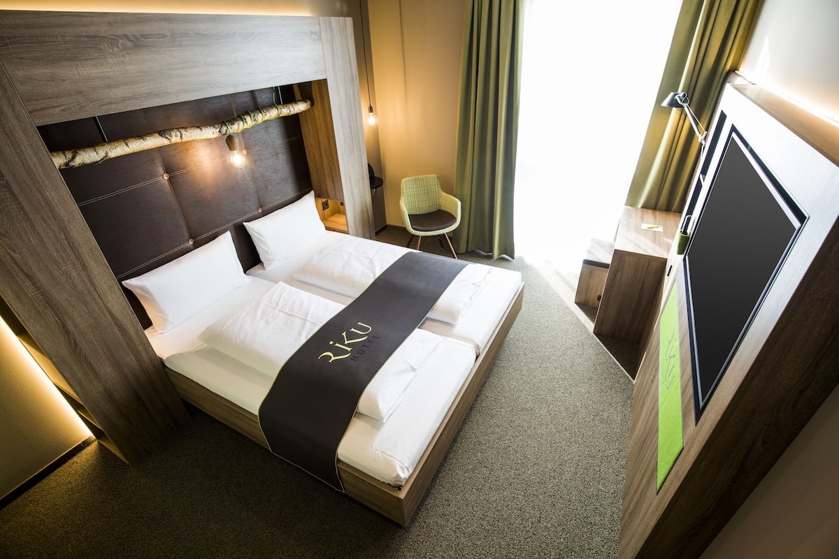 Quarto de hotel com uma cama, uma escrivaninha e uma cadeira.