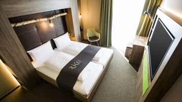 Une chambre d’hôtel avec un lit, un bureau et une chaise.
