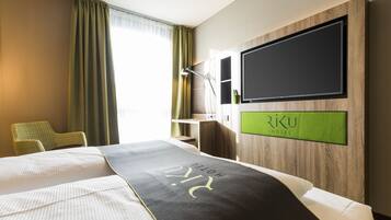 A hotel room with a bed, a desk, a chair, and a TV mounted on the wall.