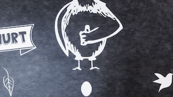 Parede de lousa com desenho de um frango, um pássaro e uma pena.