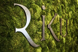 A moss-covered wall with the letters "Riku" engraved in metal.