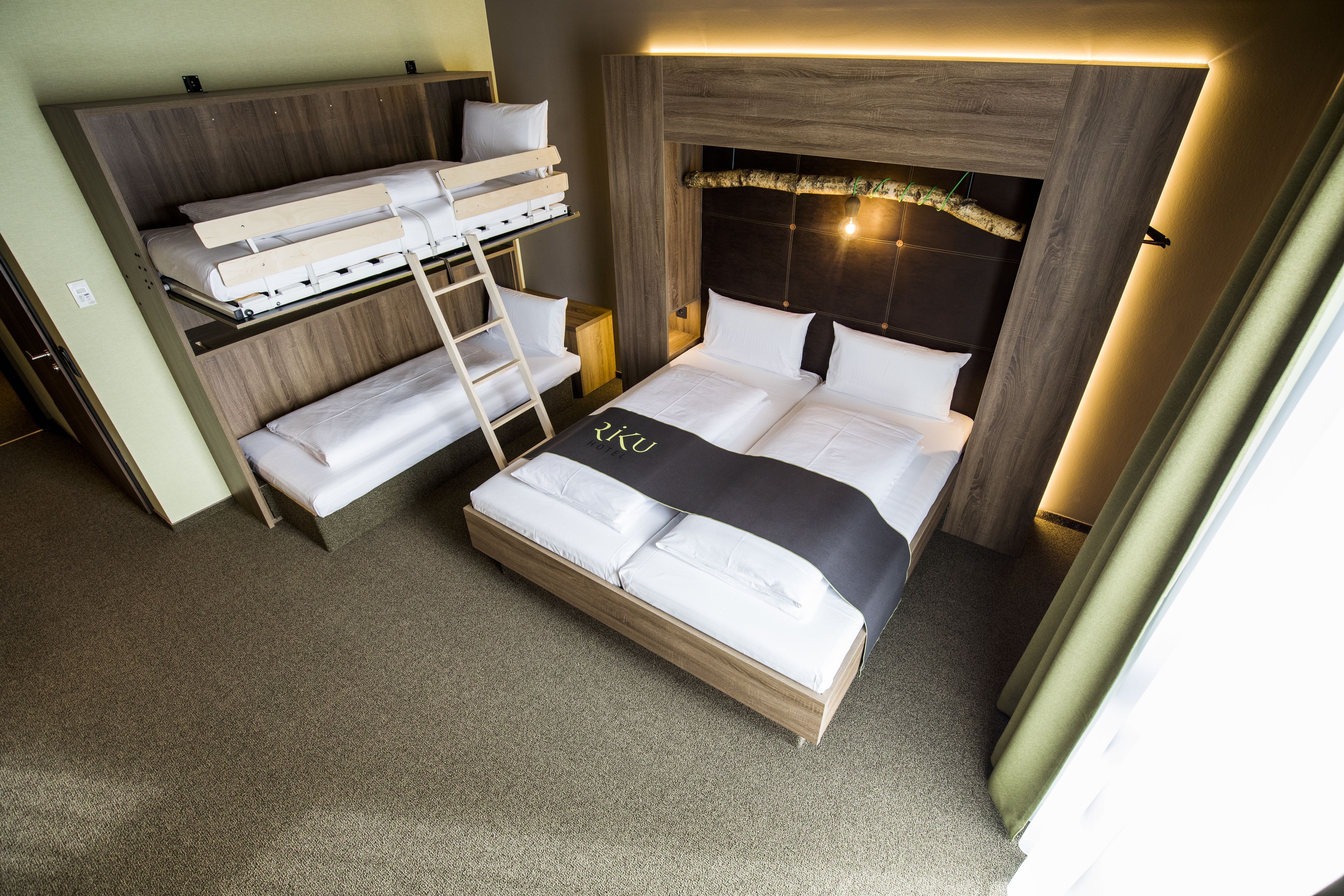 A compact hotel room with a bunk bed, a single bed, and a ladder.