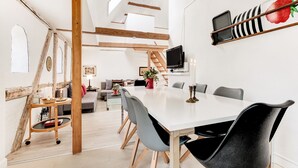 Un comedor moderno con una mesa larga, sillas grises y una estructura de techo de madera.