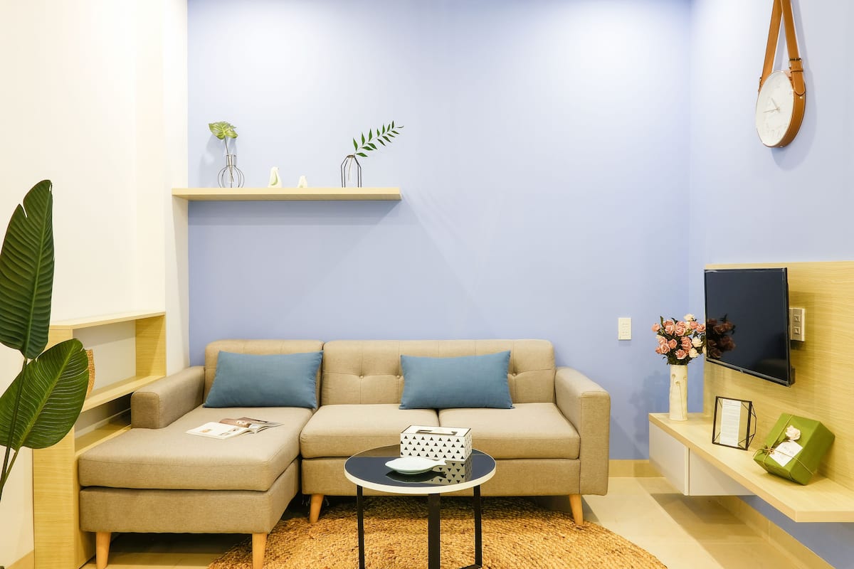 A modern living room with a sofa, a coffee table, a TV, and a shelf with decorative items.