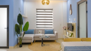 Un salon moderne avec un canapé, une table basse, une plante en pot et un téléviseur fixé au mur.