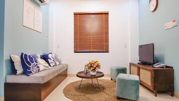 Apartemen Deluks, 2 kamar tidur, akses ke kolam renang, pemandangan kota | Ruang keluarga | Televisi LCD 32-inci dengan saluran TV kabel dan TV