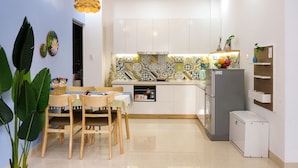 Une cuisine moderne avec des meubles blancs, un pare-feu décoré et un coin repas comprenant des chaises et une table en bois.