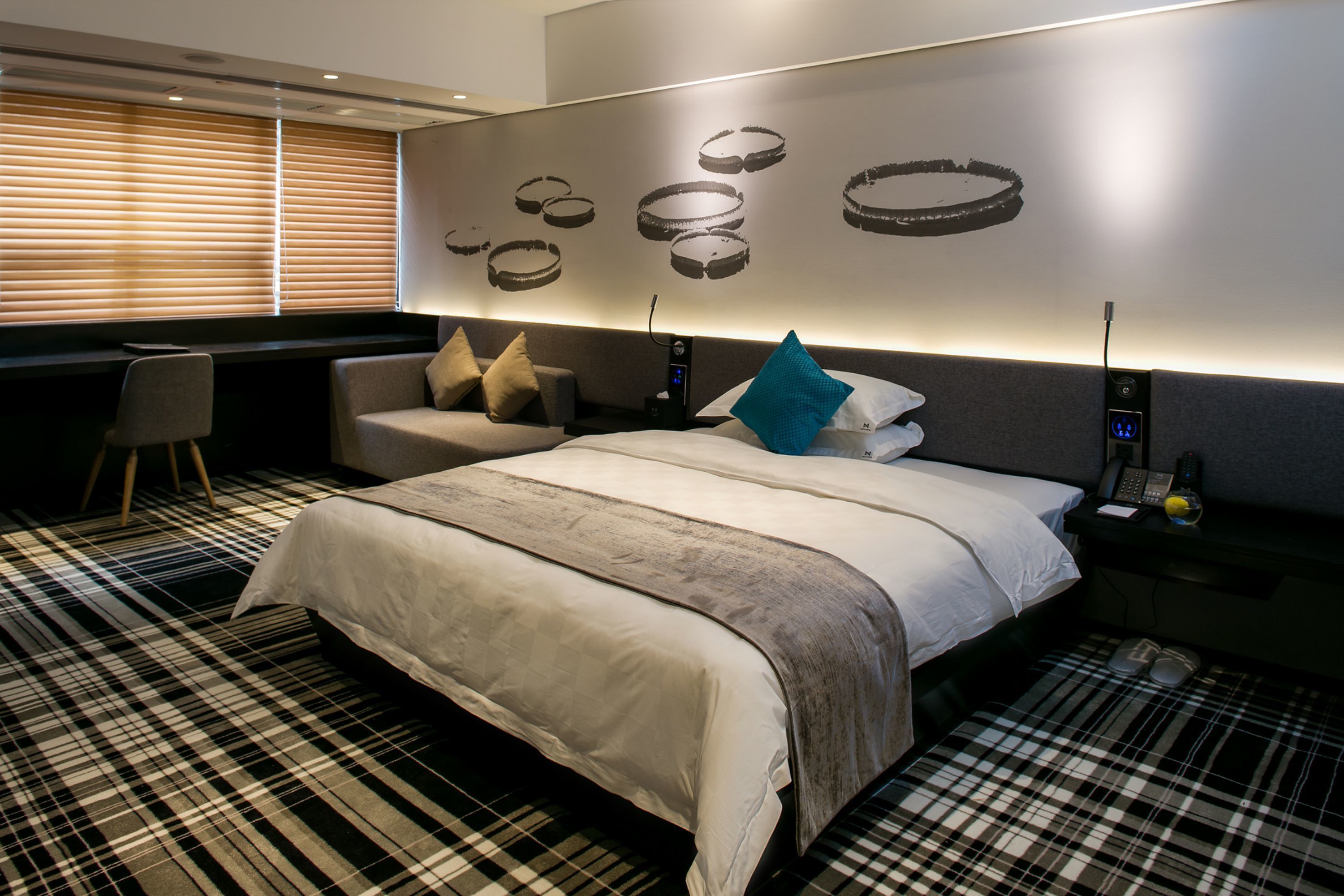 A modern hotel room with a large bed, a desk, and a seating area.