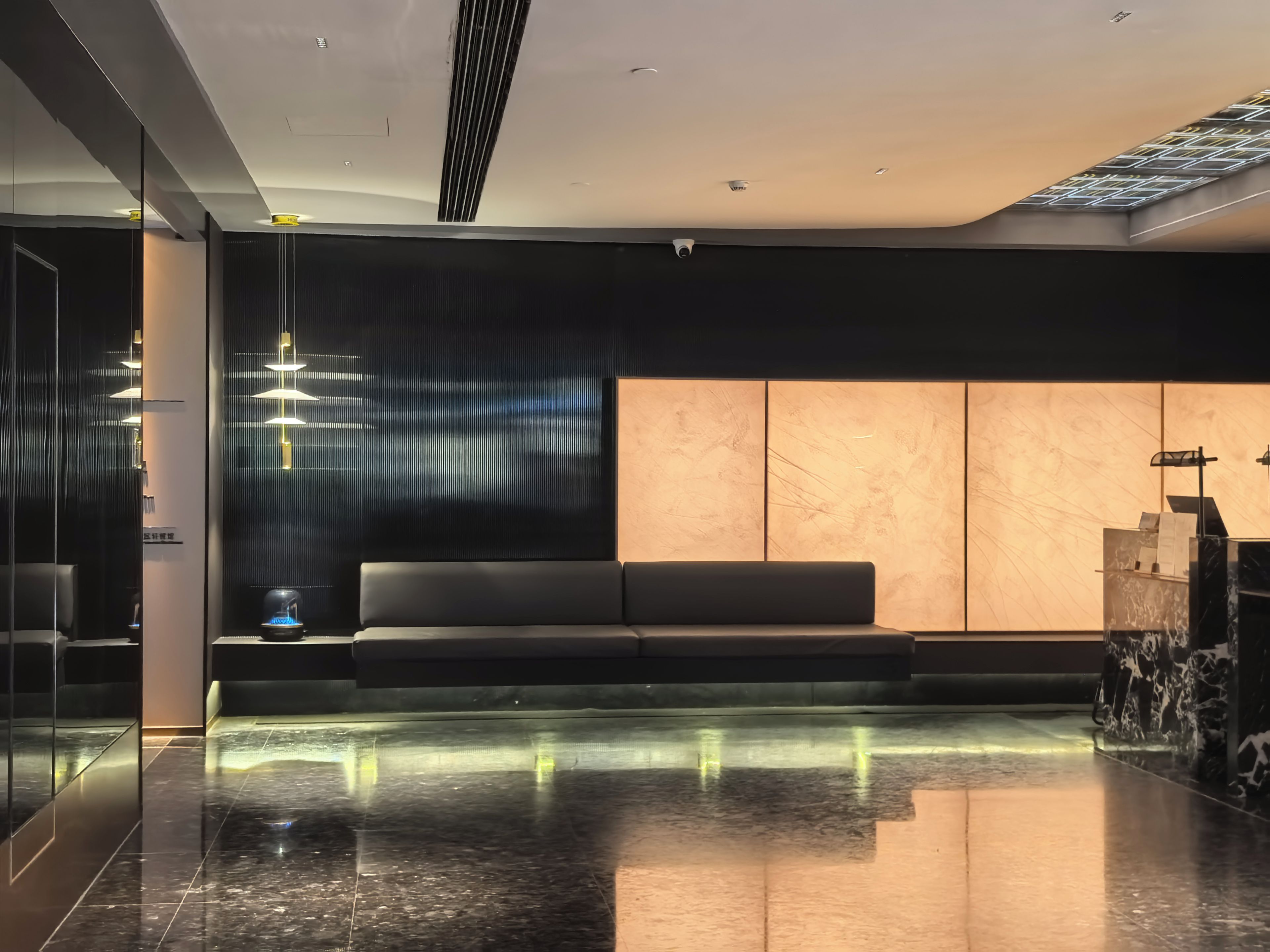 A modern lobby with a reflective floor, a seating area, and a reception desk.