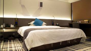 Habitación de hotel con una cama grande, un escritorio, una silla, un espejo y una ventana con persianas.