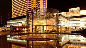 Un hotel moderno con fachada de vidrio y un llamativo letrero que dice 'LA PERLE'.