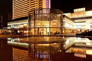 A modern hotel with a glass facade and a prominent 'LA PERLE' sign. - Likto Hotel (Guangzhou)
