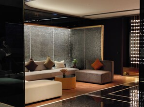 A modern lobby with a seating area featuring sofas and a coffee table, a decorative plant, and a unique light fixture. - Likto Hotel (Guangzhou)