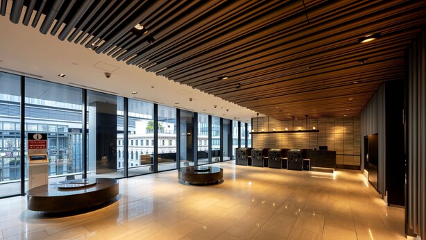 A spacious lobby with a modern design, featuring a wooden ceiling, large windows, and a reception area with a circular seating arrangement. - remm Tokyo Kyobashi (Tokyo)