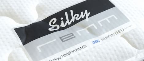 A hotel bed with a tag labeled "Silky" and "Hankyū Hanshin Hotels."