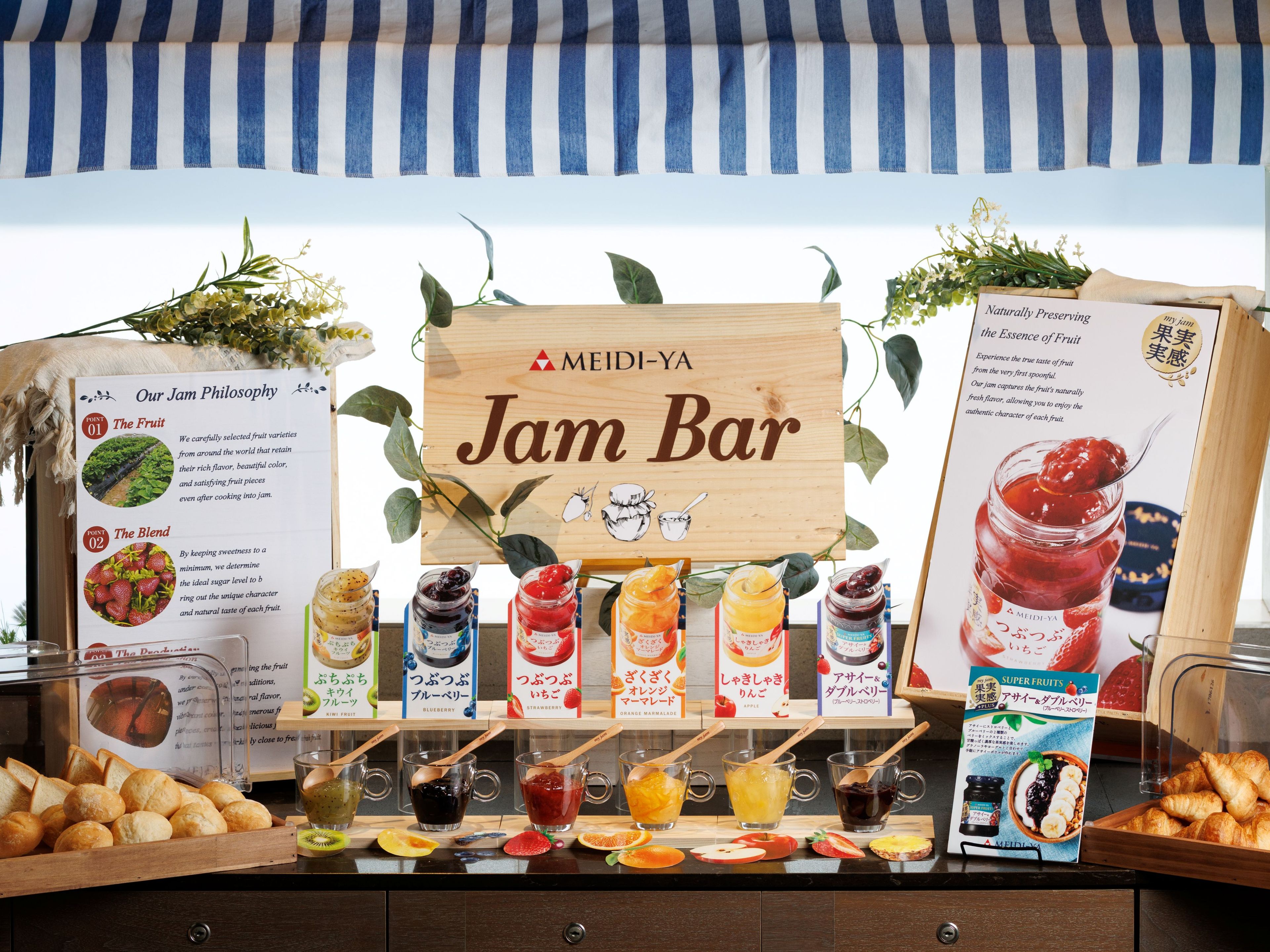 A jam bar with a wooden sign, various jars of jam, and a display of bread and pastries.