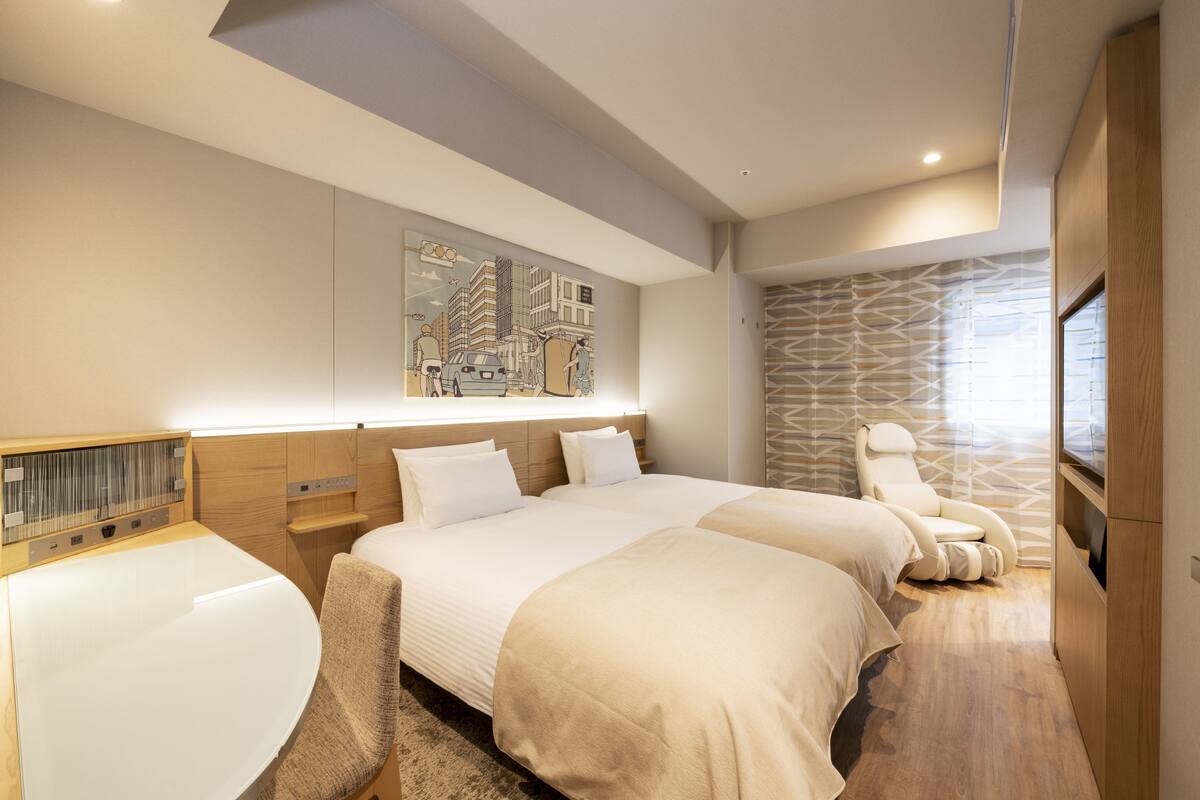 Una habitación de hotel moderna con dos camas, una silla de masaje, un ventanal grande y una obra de arte con un paisaje urbano en la pared.