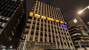 A high-rise building with illuminated signage, including a 'Pilot' sign, and a 'Pann' sign at the ground level. - remm Tokyo Kyobashi (Tokyo)