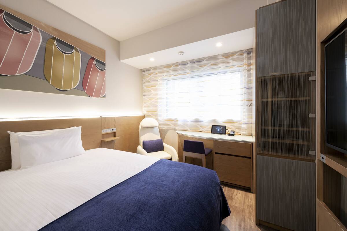 Una habitación de hotel moderna con una cama grande, un escritorio y un armario.