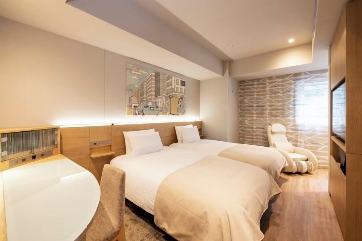 A modern hotel room with two beds, a seating area, and a stone-patterned wall.