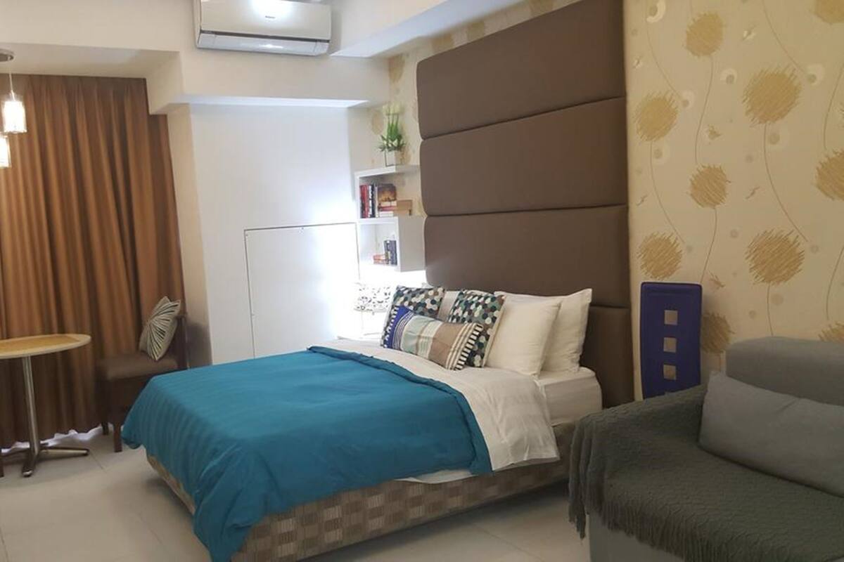 A bedroom with a bed, a desk, a chair, and a bookshelf.