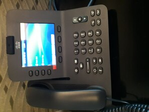 Un teléfono de oficina moderno con pantalla mostrando una interfaz de escritorio.
