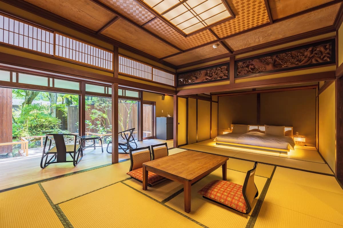 A traditional Japanese-style room with tatami flooring, a low table, and a bed with a futon.