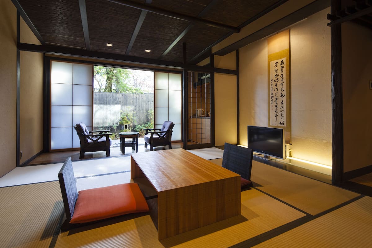 A traditional Japanese room with tatami flooring, a low wooden table, and a TV.