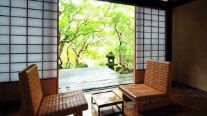 Una habitación japonesa tradicional con suelo de tatami, una mesa baja y dos sillas tejidas.