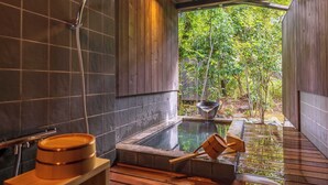 Un área de spa de madera con un jacuzzi, un cabezal de ducha y un banco de madera.
