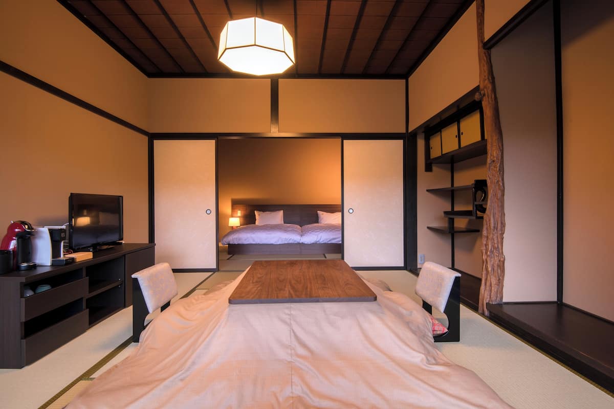 A modern hotel room with a bed, a television, a desk, and a shelf.