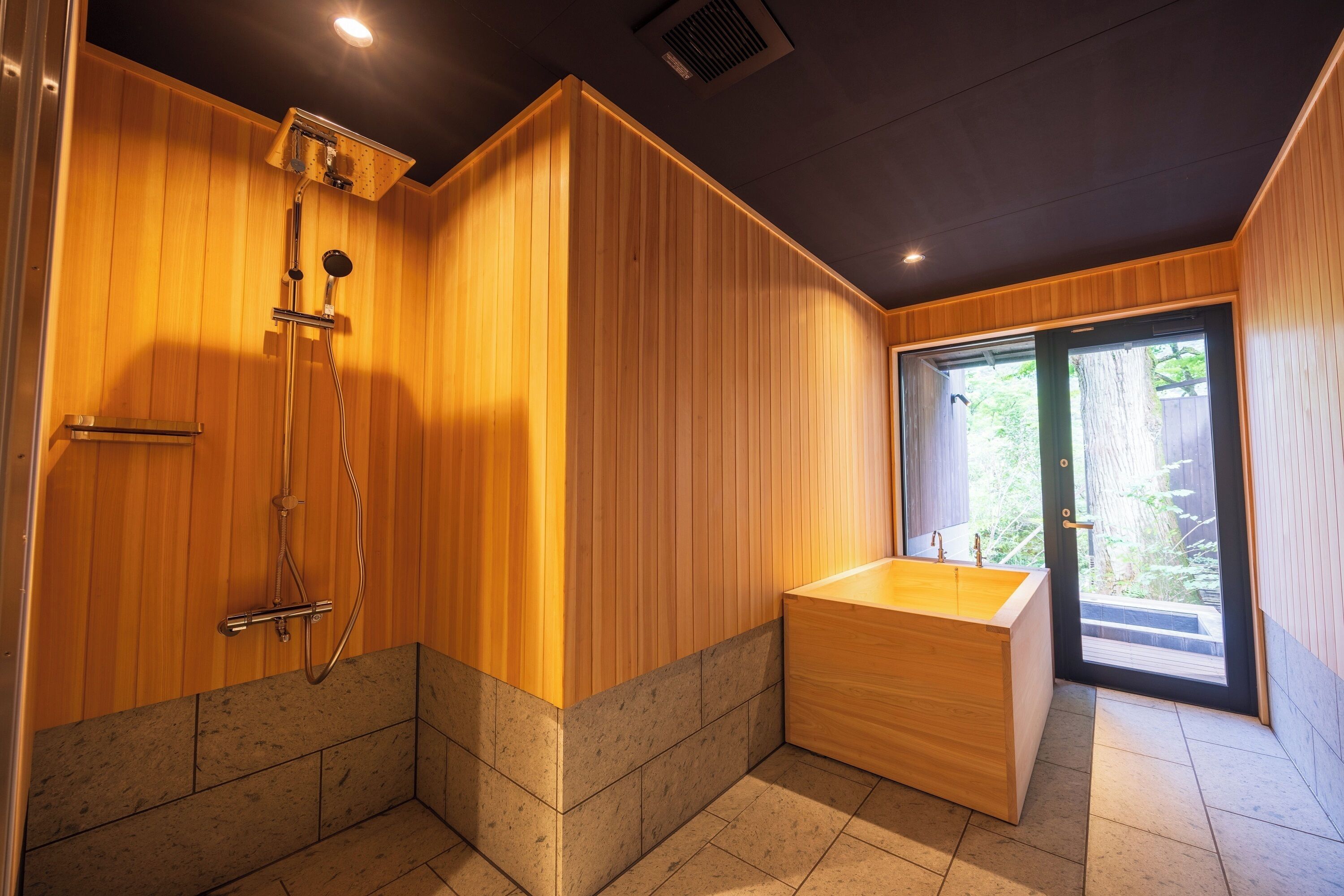 A modern bathroom with wooden walls, a freestanding bathtub, and a shower area.