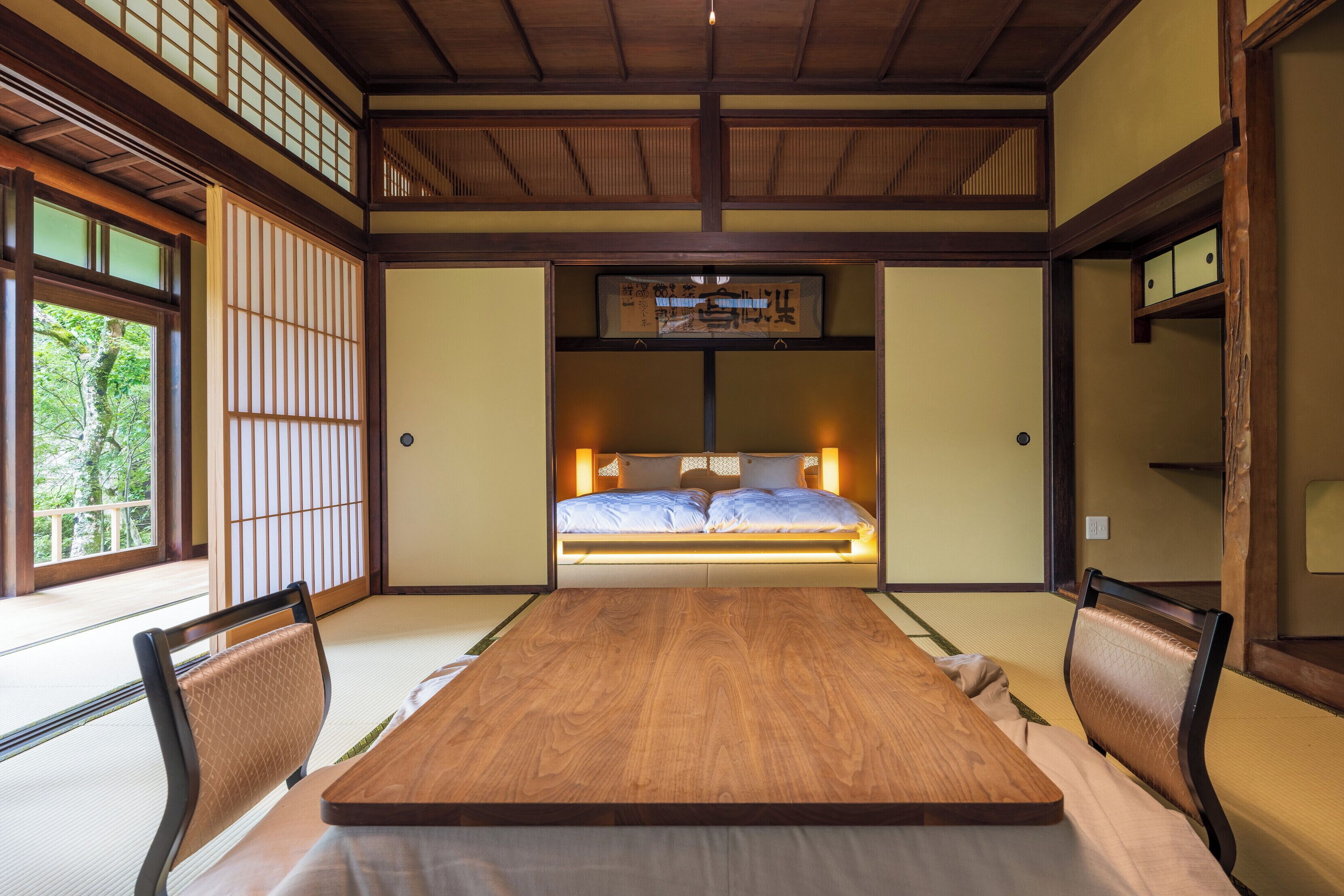 A traditional Japanese-style room with tatami flooring, a low wooden bed, and sliding shoji doors.
