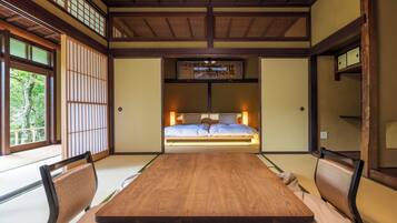 A traditional Japanese-style room with tatami flooring, a low wooden bed, and sliding shoji doors.