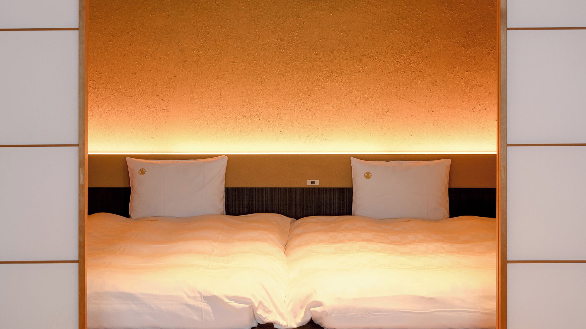 A double bed with a headboard that has a textured wall behind it.