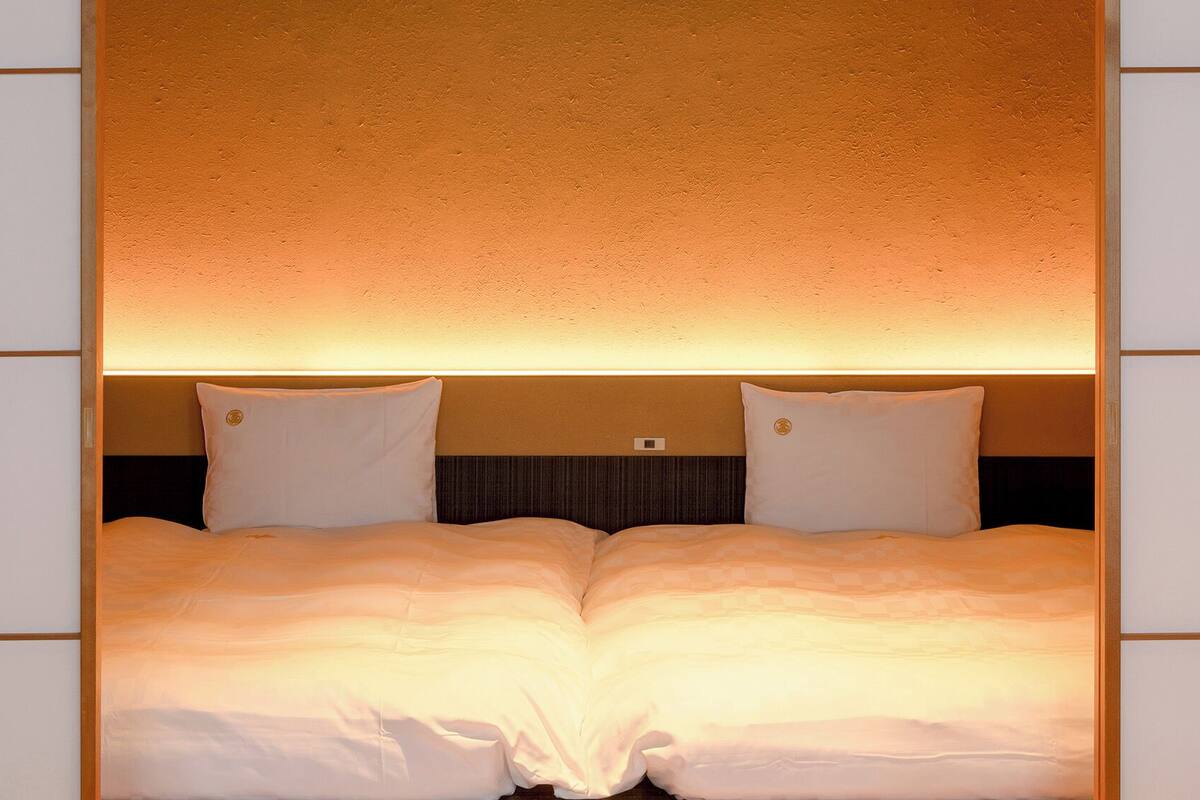 Una cama doble con cabecera y pared texturizada al fondo.