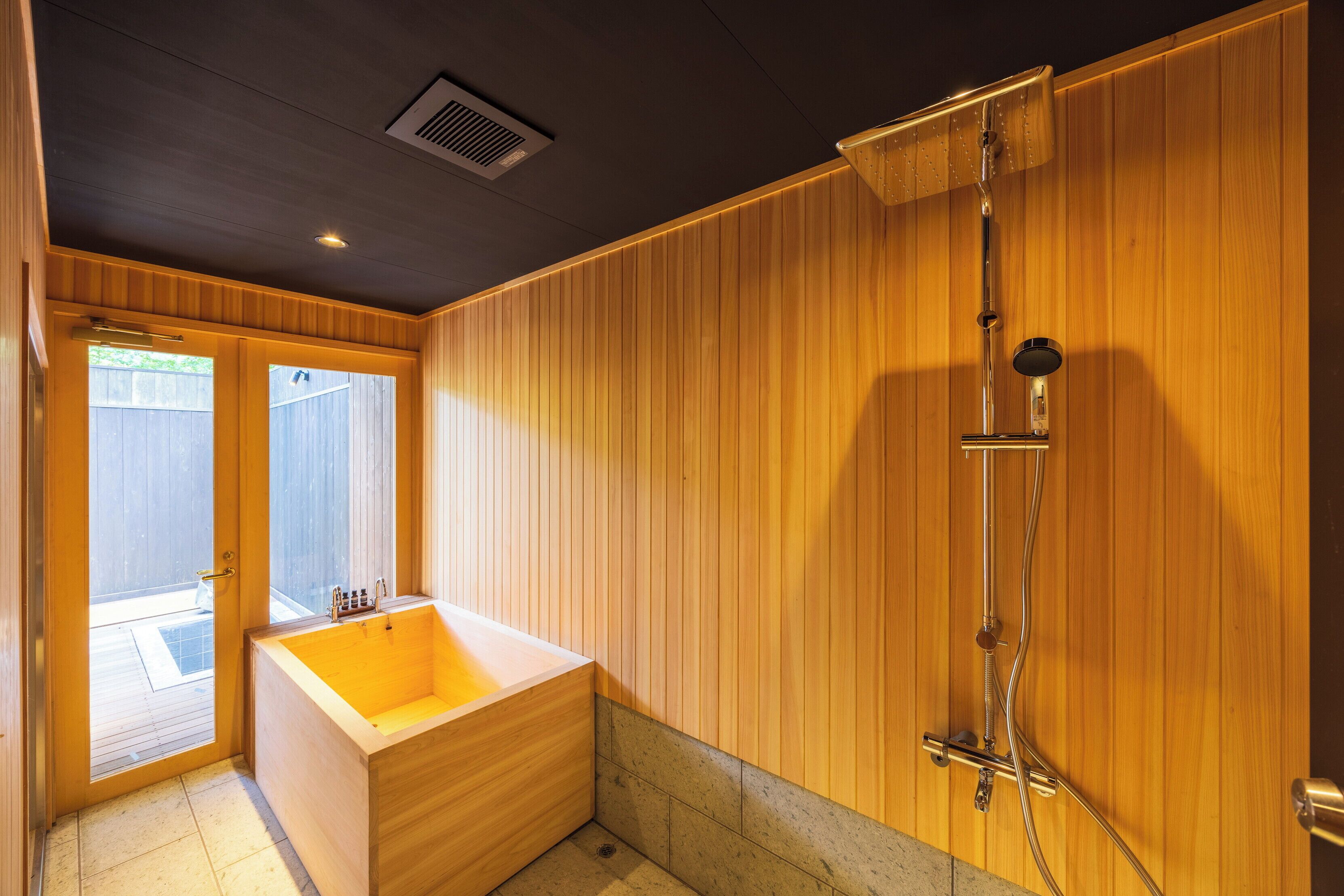 A wooden-paneled bathroom with a bathtub and a shower.