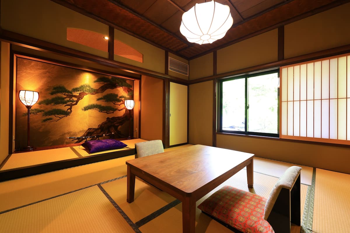 A traditional Japanese room with tatami flooring, a low table, and a view of the outdoors through shoji screens.