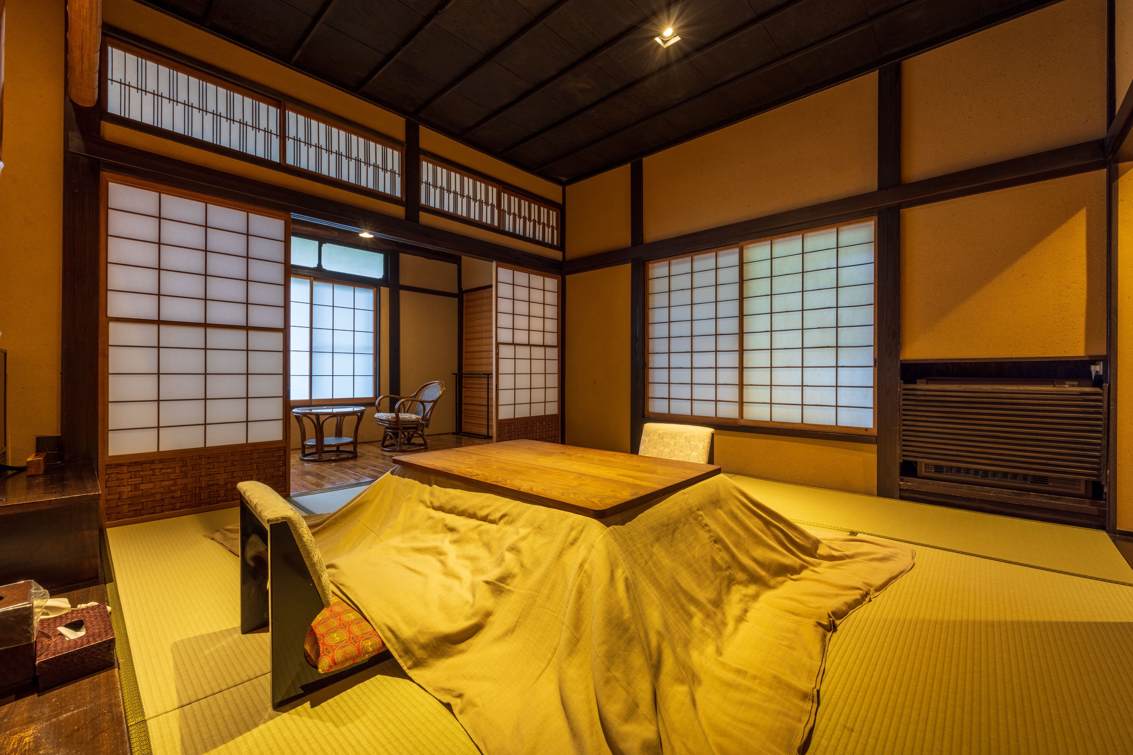 A traditional Japanese room with tatami flooring, a low table, and sliding doors.
