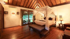 A bedroom with a wooden ceiling, a canopy bed, a bench, a bedside table with a lamp, and a view of the outdoors. - Baliana Villa Umalas (Kerobokan)