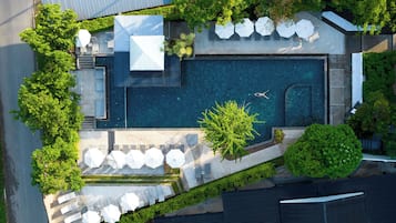 Eine Vogelperspektive zeigt einen Resort mit Schwimmbad, Außenbereich zum Sitzen und üppiger Bepflanzung.