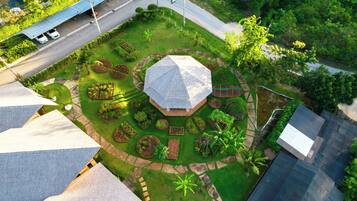Vista aérea de un jardín ajardinado con un pabellón central, rodeado de jardineras y un pequeño estanque.
