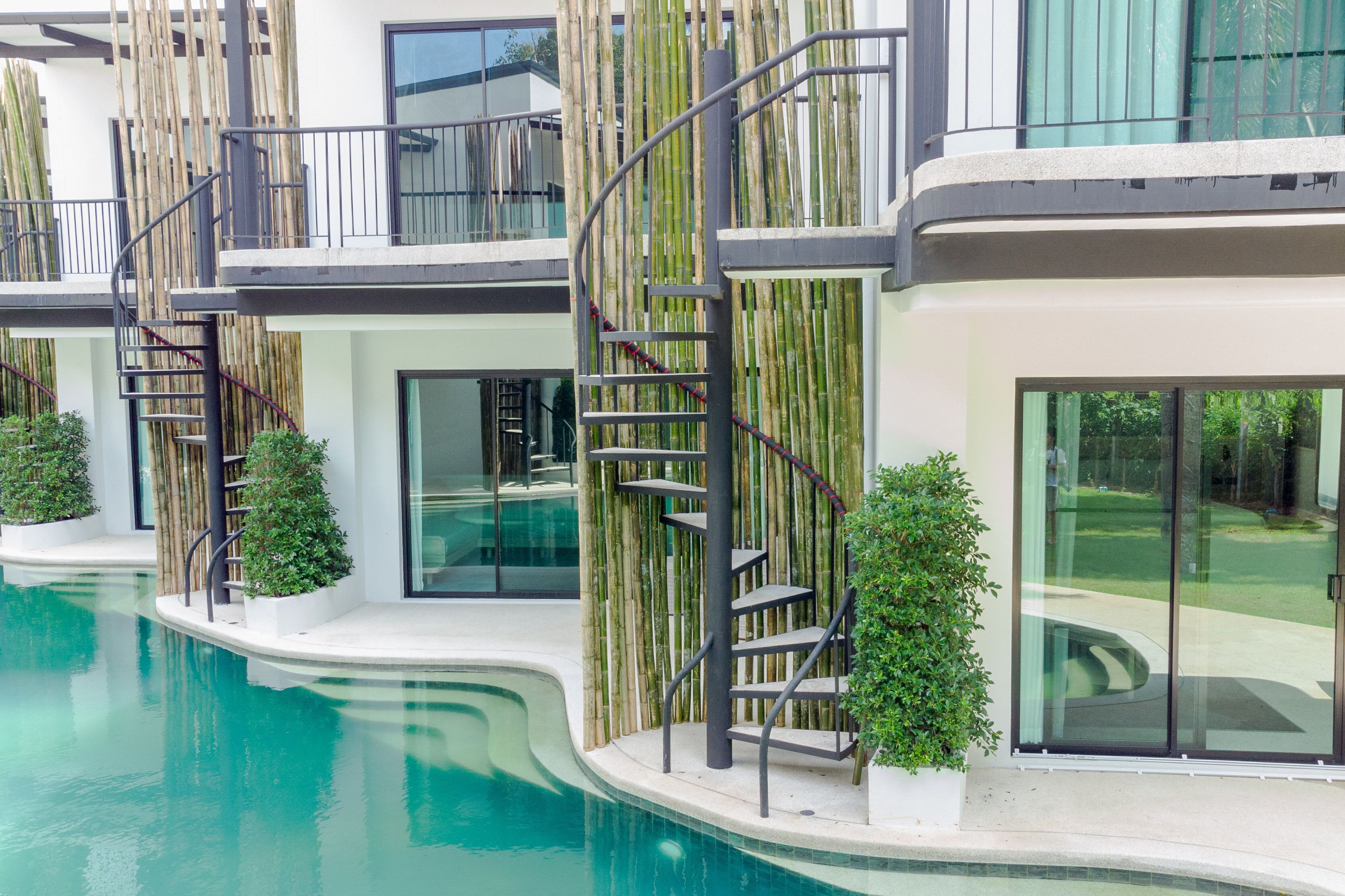 Un edificio moderno con piscina, detalles de bambú y una escalera en espiral.