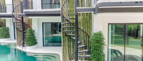 Un edificio moderno con piscina, detalles de bambú y una escalera en espiral.