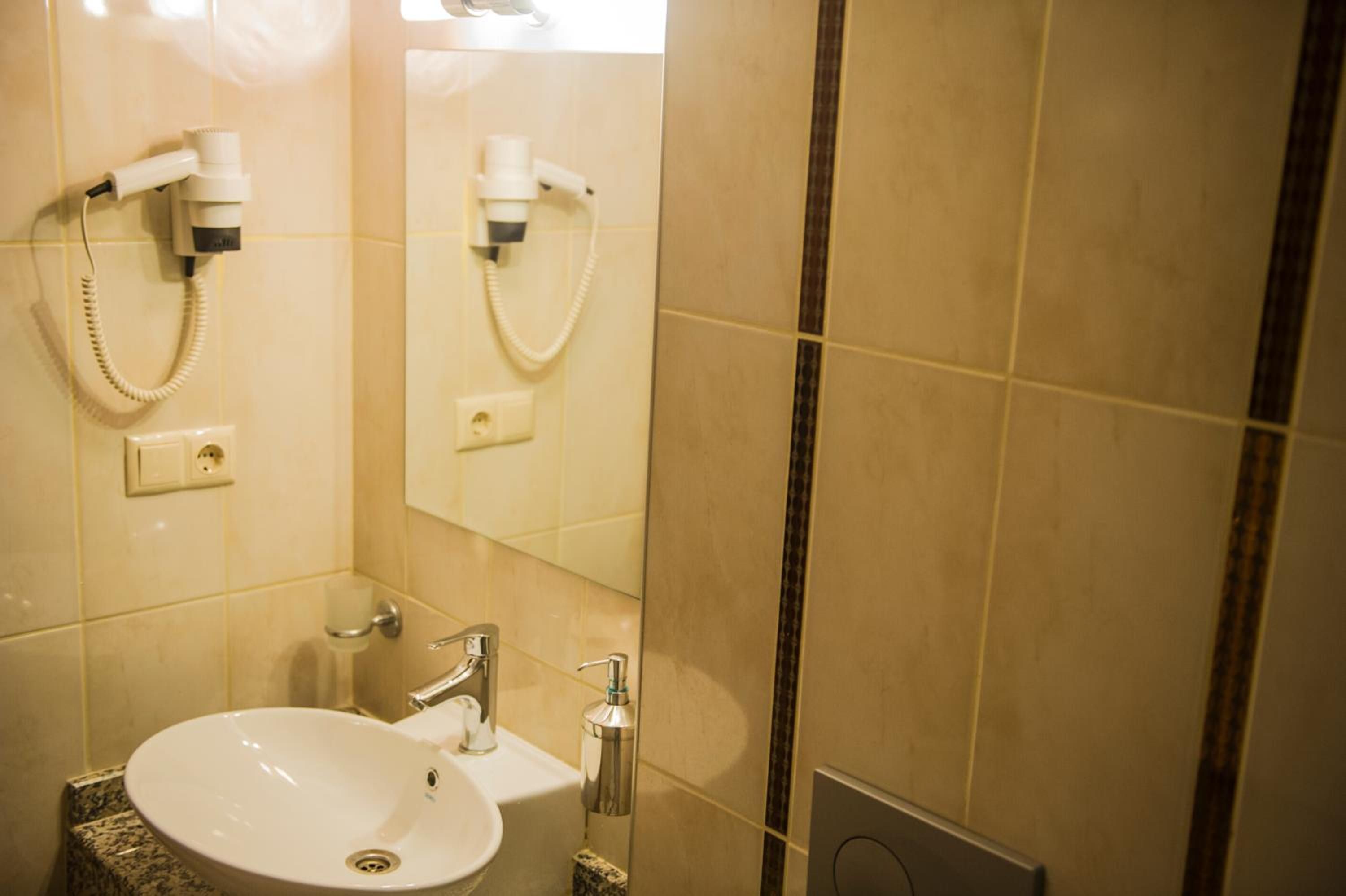 Un bagno con lavandino, specchio, asciugacapelli e porta asciugamani.