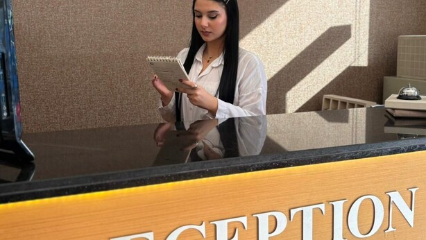 A reception desk with a sign reading "RECEPTION" and a logo for "PINAR HOTEL" on the wall behind. - Pinar Elite Hotel (Adana)